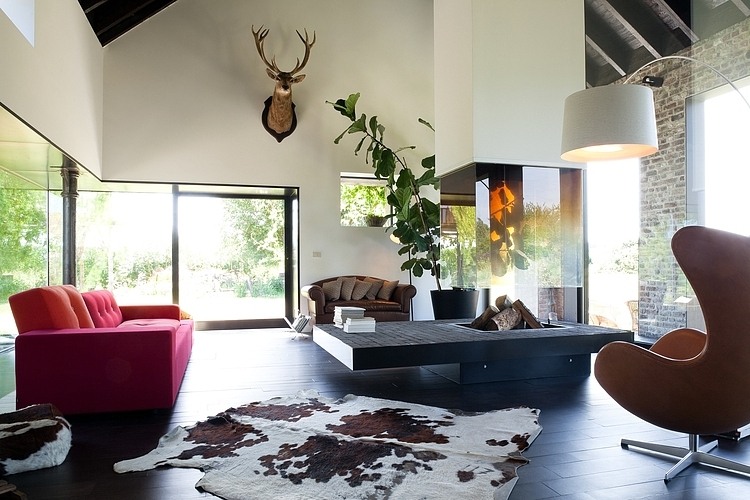 Nepřehlédnutelnou dominantou interiéru je centrálně umístěný krb. Majitelé si ho užívají z pohodlí červené sedačky Polder Sofa od švýcarské Vitry. Navrhla ji pro ni v roce 2005 nizozemská designérka Hella Jongerius. 